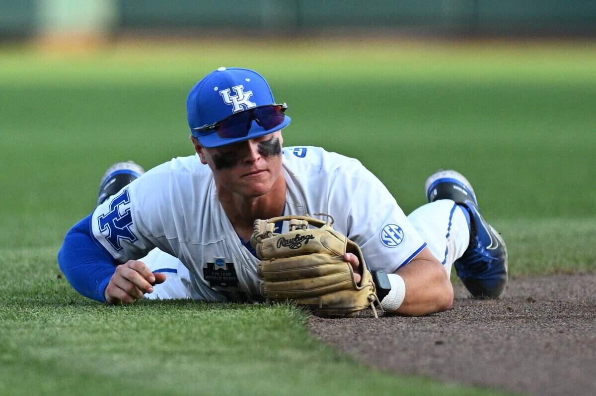Jun 17, 2024; Omaha, NE, USA;  Kentucky Wildcats shortstop Grant Smith (12) dives for a ground ball against the Texas A&M Aggies during the fifth inning at Charles Schwab Field Omaha. Mandatory Credit: Steven Branscombe-USA TODAY Sports