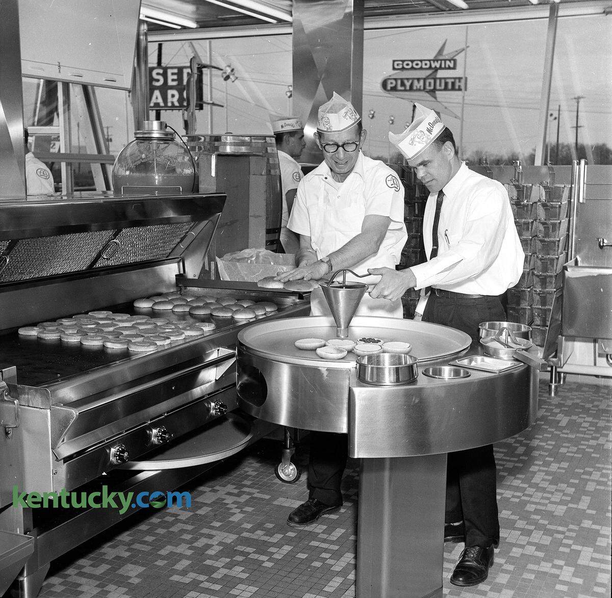 Sam Smargon, left, owner and manager, and Gene Witheril, company field consultant, turn out some hamburgers at Lexington’s first McDonald’s in December 1961. The drive-in fast-food hamburger restaurant, located at 771 East New Circle Road, near Eastland Drive, opened Dec. 12 that year. It was the 306th Golden Arches to open nationwide in 37 states. The restaurant featured a limited 10-item menu the company said enabled it to serve people fast and keep costs down. Featuring a hamburger for 15 cents, McDonald’s limited its offerings to three food items - hamburgers, cheeseburgers and 10-cent french fries. Seven drinks were offered: milk shakes, Coca-Cola, root beer, orangeade, milk, coffee and hot chocolate. Their assembly-line technique promised delivery of a full meal in 50 seconds. The company said the cost for an average meal was 45 cents, which is $3.72 today adjusted for inflation. The restaurant featured no carhops or waitresses, instead letting customers get their own orders from a self-service window. The company promoted this in its low prices and no need to tip. The walls were a 900-square-foot expanse of plate glass, making “exhibition cooking” a feature of the McDonald’s. Some of that glass can be seen in this image with the Goodwin Plymouth sign in the background. Want-ads in the Lexington Leader for jobs at this New Circle location asked “for qualified young men of above average intelligence” and “no drinkers”. Herald-Leader archive photo