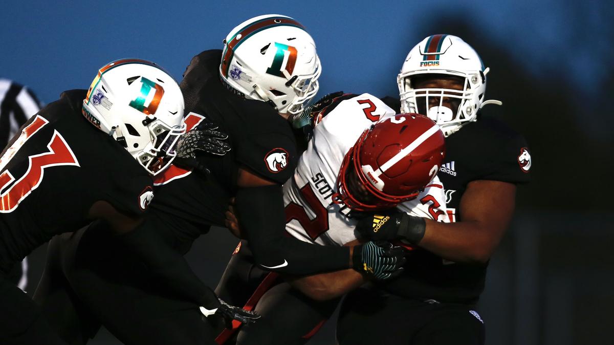 A group of Frederick Douglass defenders, including Ty Bryant (13) and Caden Johnson (6) tackled Scott County running back Montago Jones Friday, Sept. 24, 2021 at Frederick Douglass High School in Lexington, Ky.