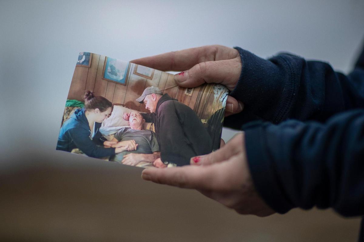 Toskia Adamson holds a photograph of herself, left, her late dad, Bert Adamson, and her older brother, Larry Adamson, that was lost when a tornado destroyed her mother’s home in Dawson Springs, Ky., on Dec. 10, 2021, during the historic quad-state tornadoes that scoured a path of destruction nearly 200 miles. Adamson was able to recover some photos that had been blown across state lines through a Facebook group dedicated to helping reunite tornado victims with lost items.