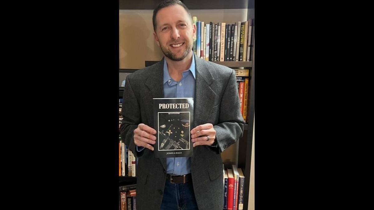 Joshua Hale, a former major with the Richmond Police Department, poses with his new book, PROTECTED. 
