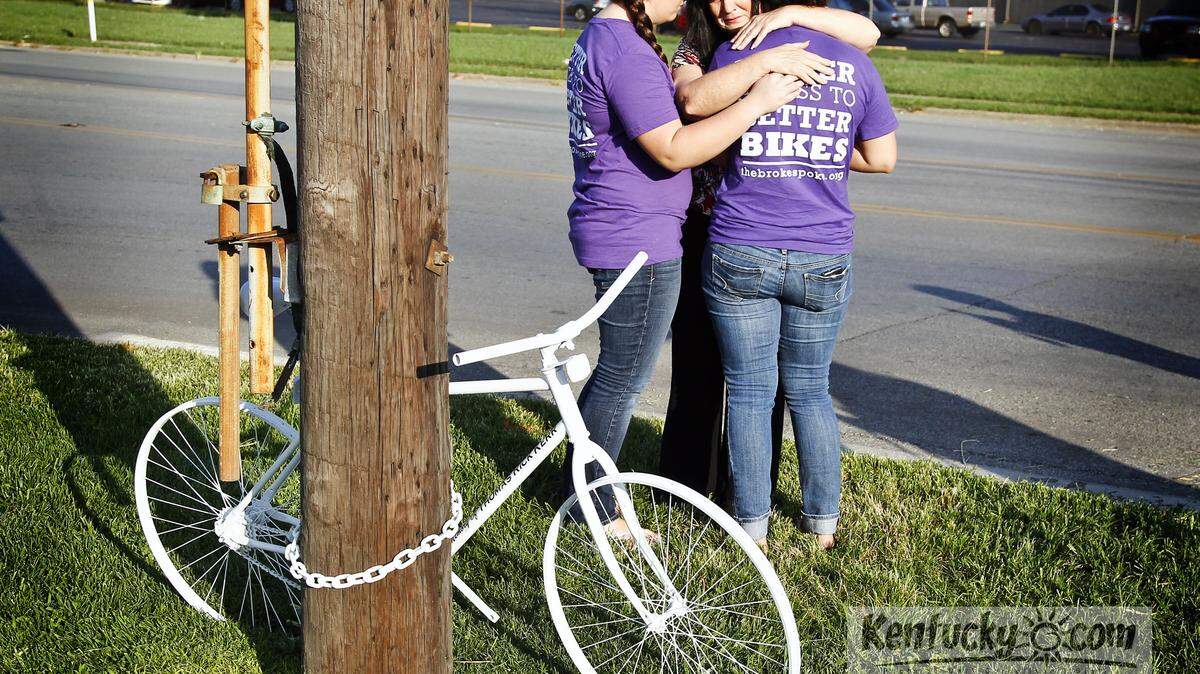 Denise Kerr, center, hugged her daughters Tiffany, left, and Jennifer, right, as friends and family gathered to place the ghost bike for Rick Kerr on Russell Cave Road near where he was killed in 2012. Photo by Mark Cornelison | Staff