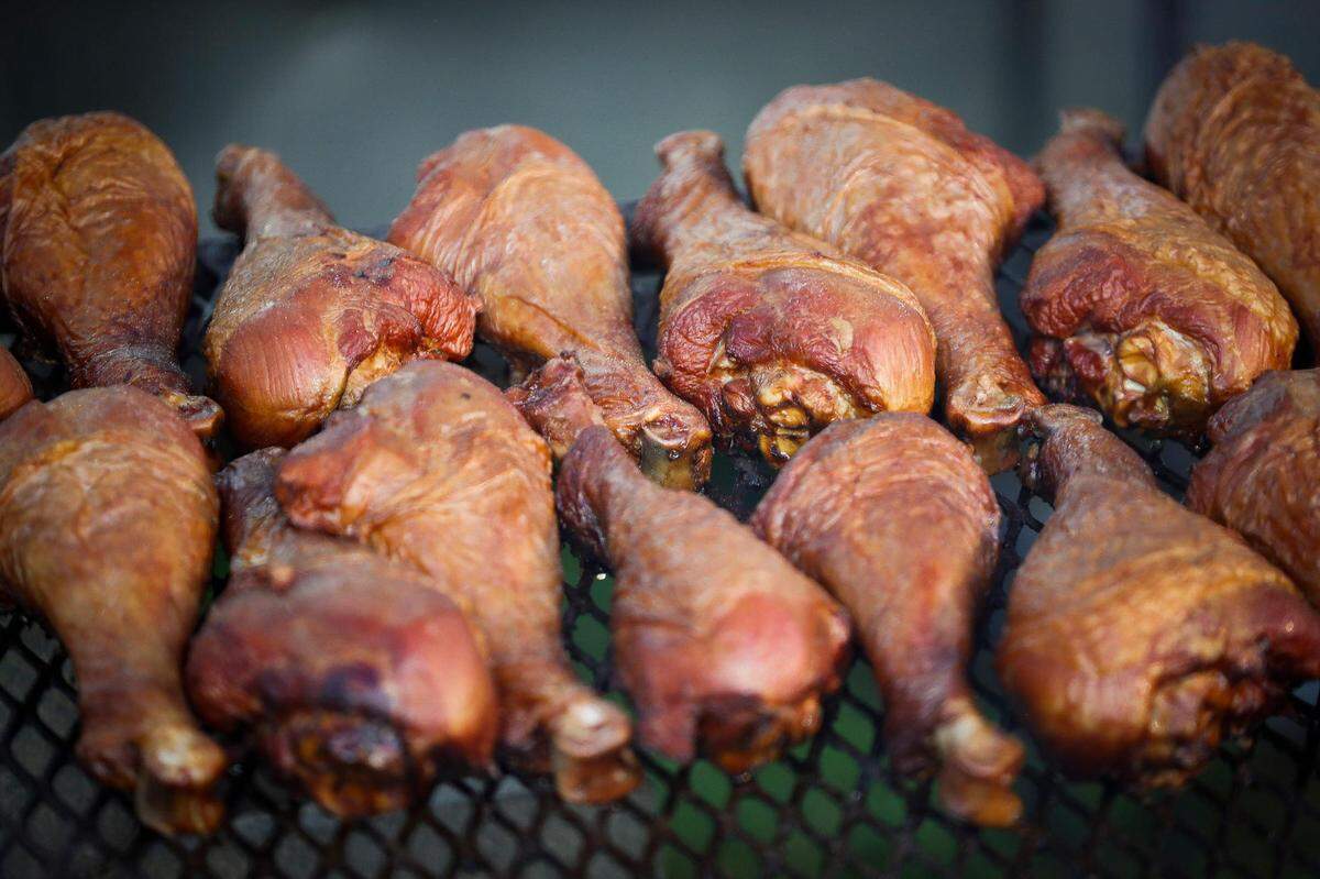 Dozens of sugar cured turkey legs sit over charcoal after being coated in barbecue sauce at Georges Fun Foods at the Lexington Lions Club’s Bluegrass Fair at Masterson Station Park in Lexington, Ky., Friday, June 11, 2021.
