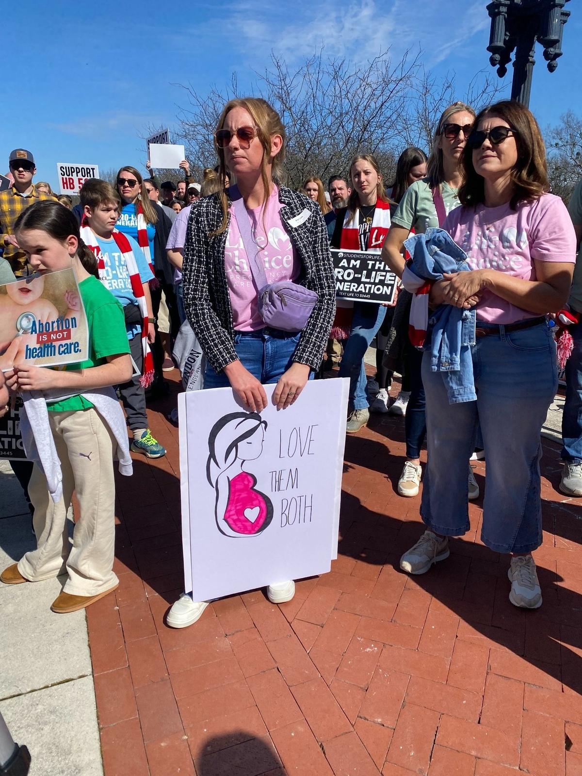 An attendee at a March for Life rally at the Kentucky Capitol on Wednesday holds a sign that says, “love them both.”