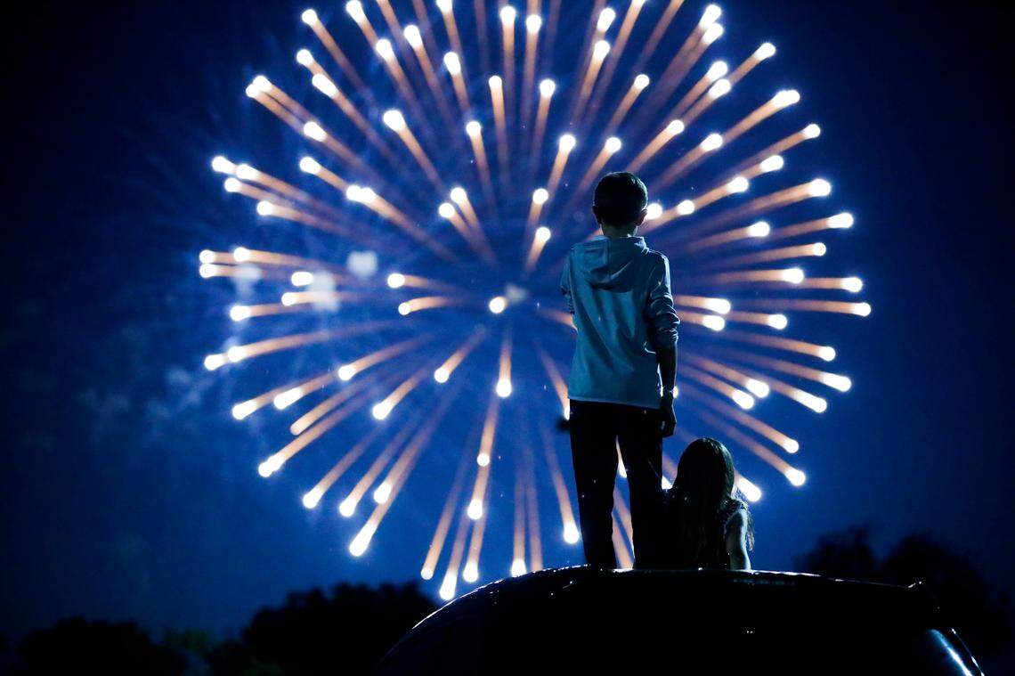 Mays Bledsoe, 12, left, and Annabeth Bledsoe, 9, both of Lexington, Ky., watch the city of Lexington’s Fourth of July fireworks display from the Lexington Center parking lot in Lexington, Saturday, July 4, 2020.