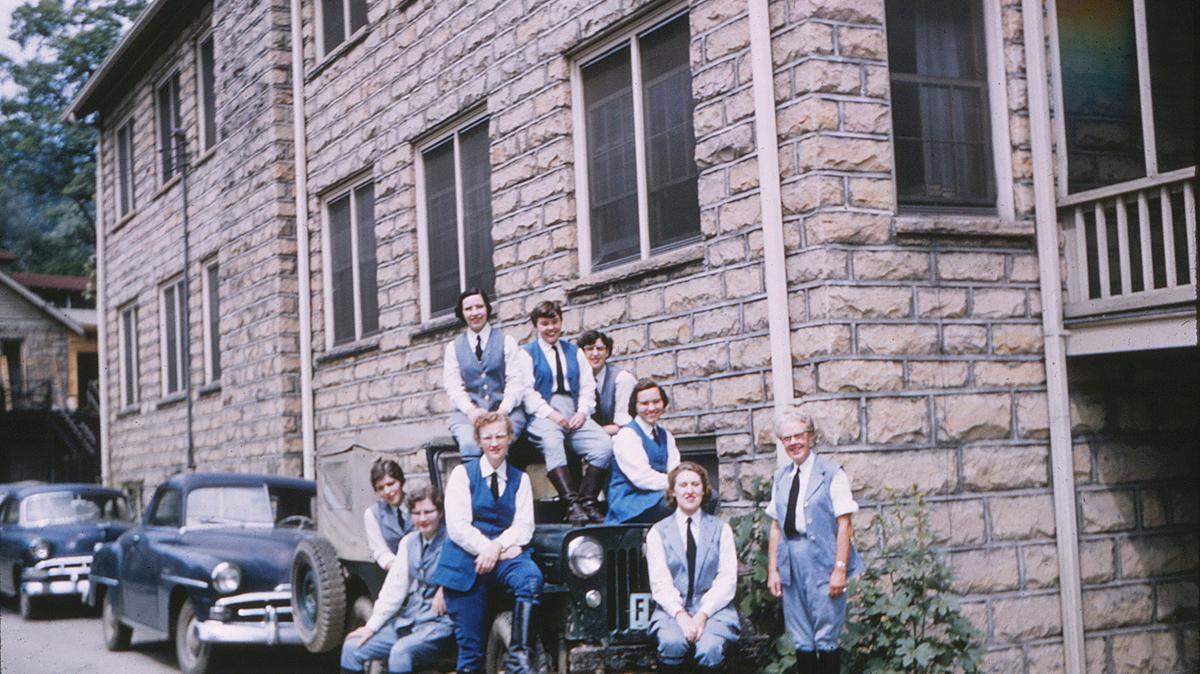 The 1957 graduating class wore their Frontier Nursing Service  uniforms. They are next to Haggin Dormitory, a building still in use at the Frontier Nursing University campus in Leslie County. 