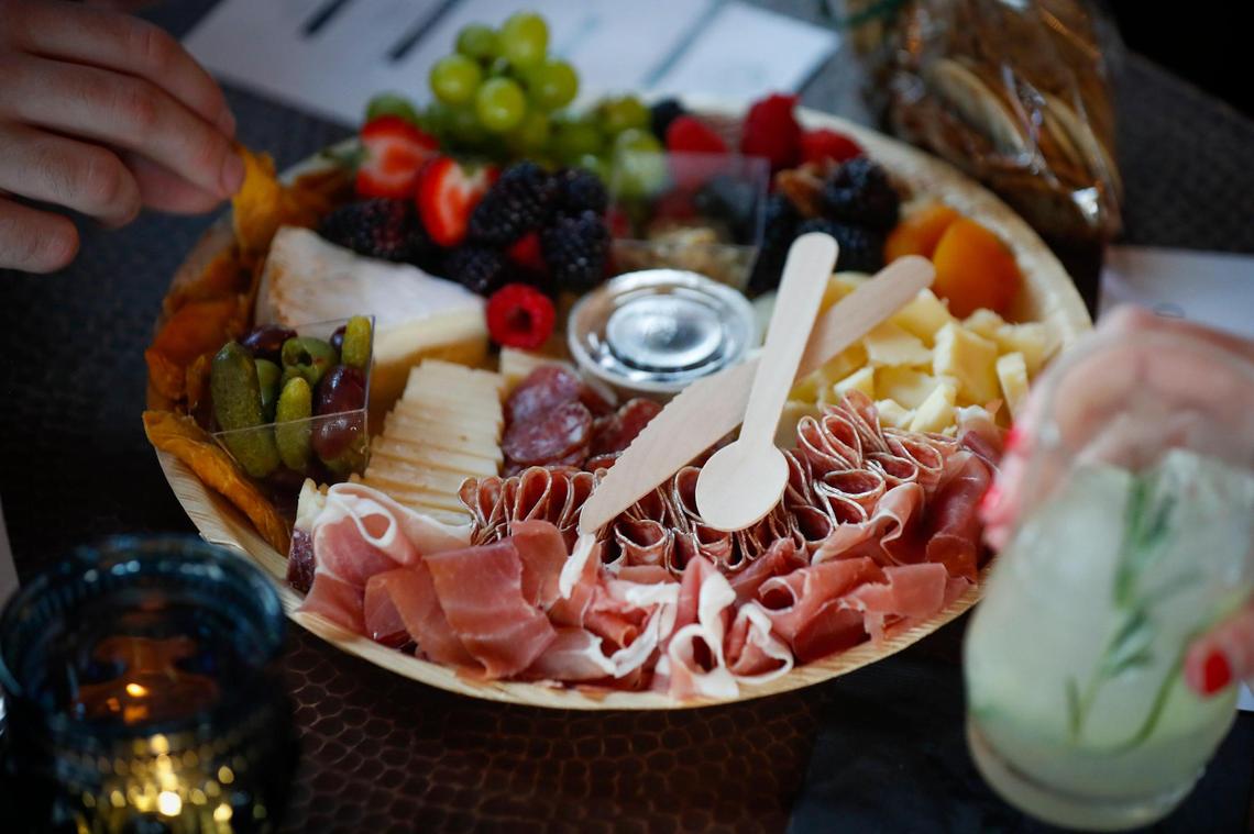 Justin Ratcliff and Katlin Massie, both of Lexington, Ky.. share a charcuterie board made with three meats, three types of cheese, fresh and dried fruit, olives and pickles, nuts, mustard, jam, honey and served with crackers from Fable at The Grove in Lexington, Thursday, May 27, 2021. The Grove is collaboration space between Harvey’s Bar and beer garden, Fable, which offers wine and charcuterie boards, Luna, a food truck and a new event space called The Melodeon.