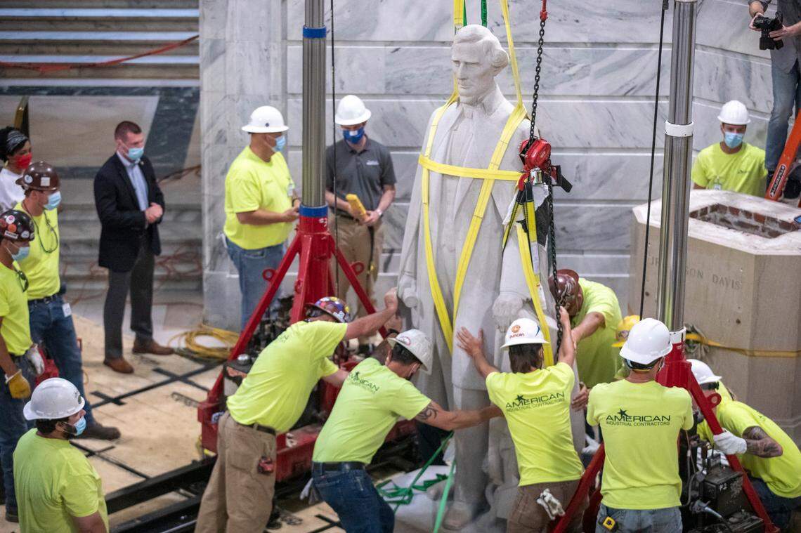 Workers remove the Jefferson Davis statue from its pedestal in the rotunda at the Kentucky state Capitol in Frankfort, Ky., on Saturday, June 13, 2020.