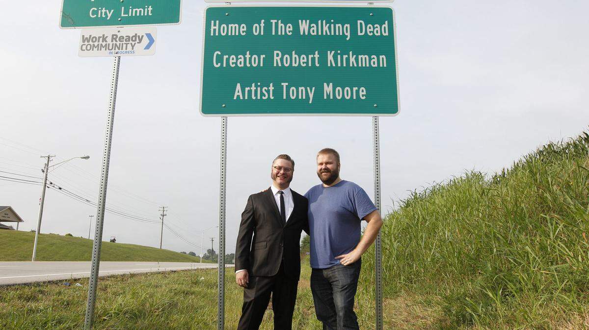 Comic book writer Robert Kirkman and artist Tony Moore stand in front the city welcome sign that includes their names on Saturday, August 5, 2016, before the opening of The Walking Dead Day in downtown Cynthiana, Ky.