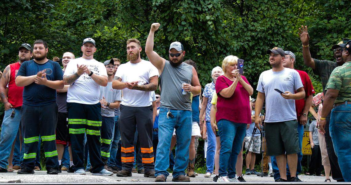 Chris Rowe, center, holds his fist up in victory Wednesday after two CSX train engines passed on the tracks with no coal cars in tow. Rowe and several other former Blackjewel coal miners in Harlan County had been protesting for three days by halting coal trains from passing after their former employer had failed to pay them their last paychecks.
