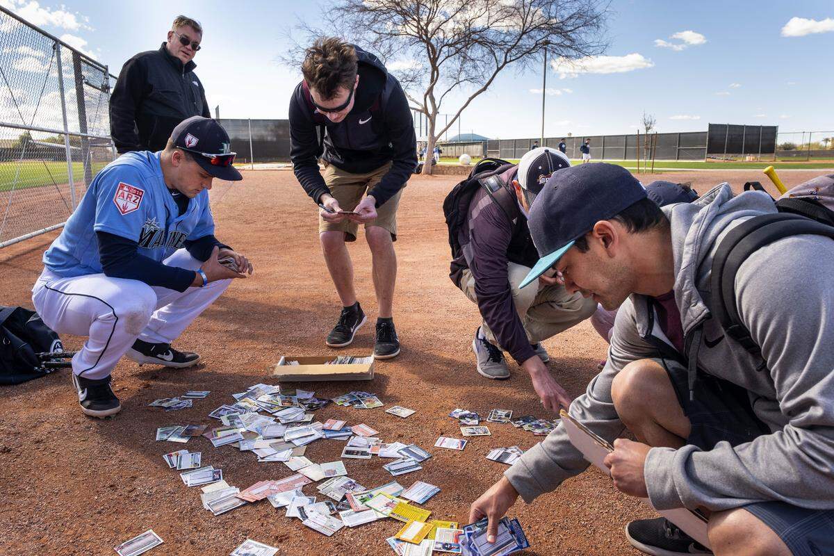 Seattle Mariners infielder Evan White came to the aid of Nik Jarvinen, center, whose box of baseball cards went flying when he tried to get the former Kentucky star’s autograph Saturday.