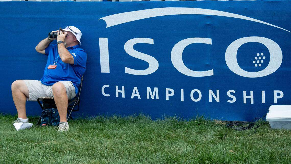 A volunteer uses binoculars to look at golfers across a lake during the 2024 ISCO Championship at Champions at Keene Trace Golf Club in Nicholasville. The tournament has moved to Louisville and gets underway this week.