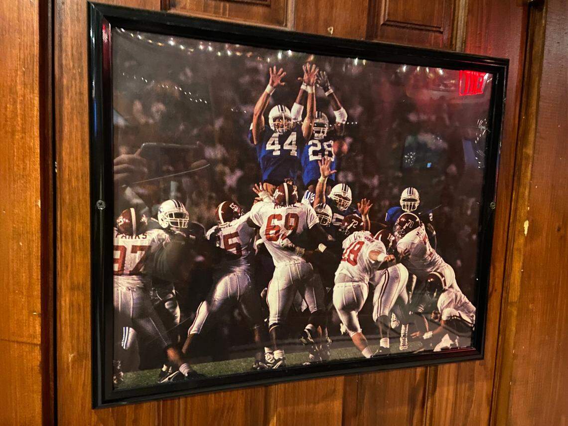 A framed photograph of former Kentucky football player David Ginn’s famed field goal block against Alabama in 1997 is shown inside Jack Demsey’s in New York City. All Kentucky football games are shown inside the multi-level bar and restaurant in Manhattan.