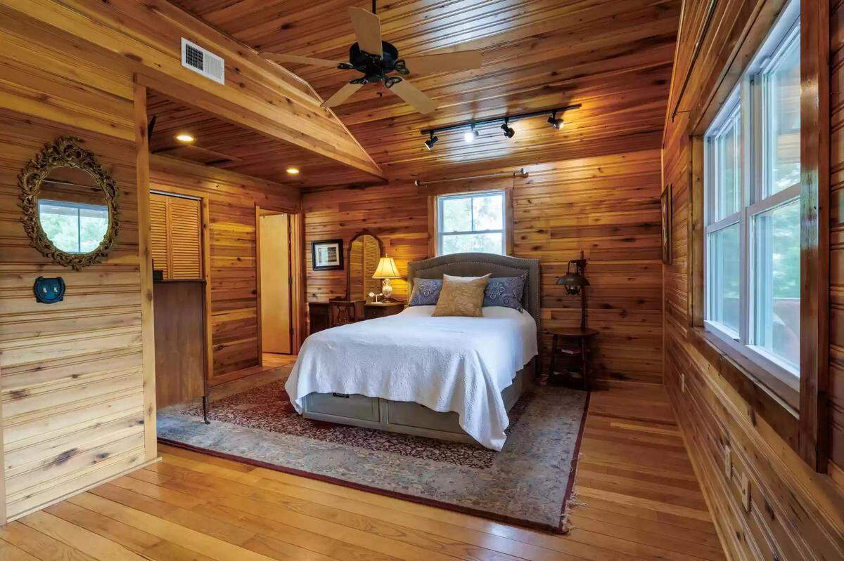 A view of a bedroom at 4351 Bethel Road, with its walls made of warm wood. 