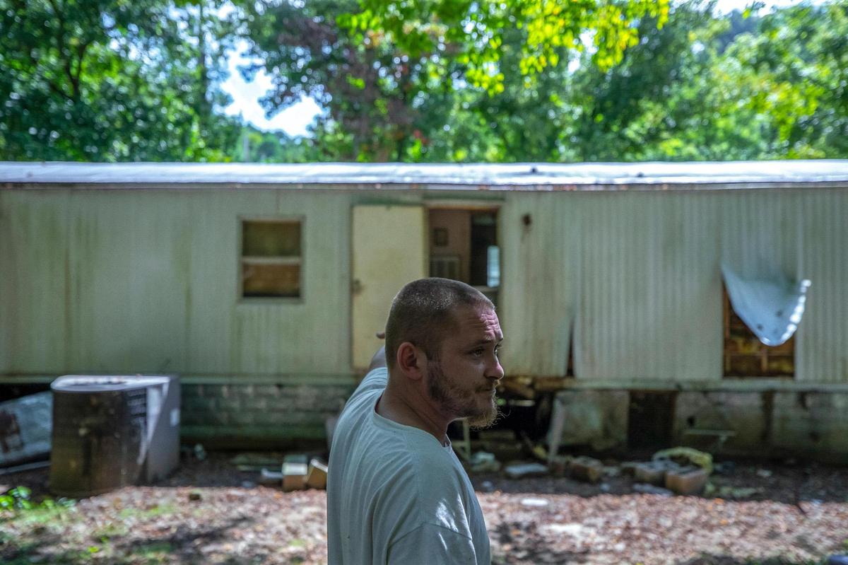 Wiley Messer, 31, points to his home in Perry County, Ky., that was damaged by flooding last month. Messer and his girlfriend, Emerald Hensley, 33, sometimes sleep in a tent in their yard and other times in his SUV.