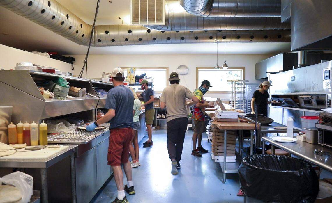 Employees create and bake pizzas for customers July 14 in the kitchen of Miguel’s Pizza in Slade. Many of the employees are seasonal climbers who come to live and work at Miguel’s so they can spend their free time rock climbing in Red River Gorge.