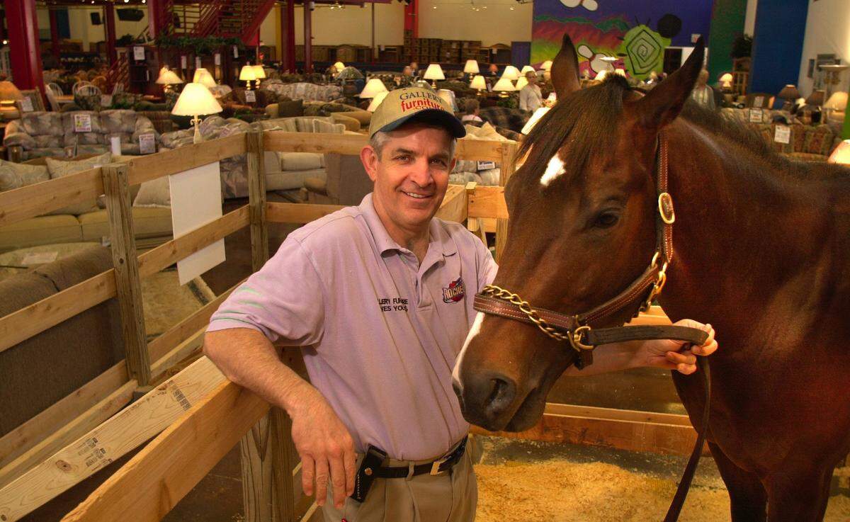 Jim McIngvale stands with Some Actor, one of his Thoroughbreds, in a makeshift pen in the showroom at Gallery Furniture in Houston in 2000. Some Actor was on display in the store while recovering from a hoof injury.