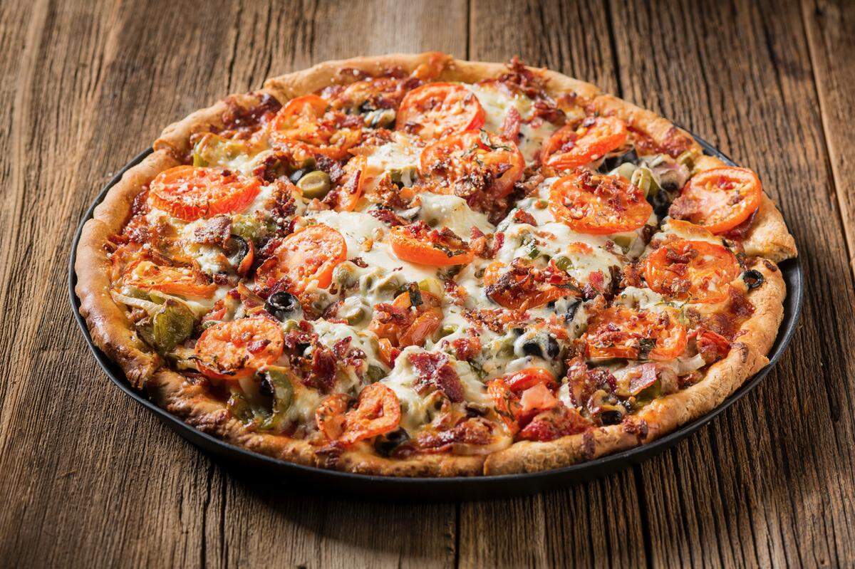 The Rosati’s Monster, a Chicago-style thin crust pizza topped with gourmet Italian sausage, pepperoni, mushroom, onion, green pepper, Canadian bacon, meatball, black and green olives with tomato and bacon on top.