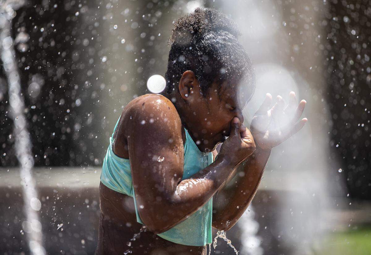 Members of Total Grace Church’s Achievers Academy cool off at the fountain at Courthouse Square in downtown Lexington Thursday, June 27, 2019.
