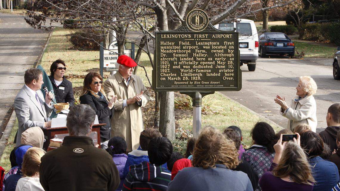 A historical marker on the site of Lexington's first airport was unveiled Monday at Boiling Springs Drive and Leestown Road with help from Sam Halley (red cap), a grandson of the airport's  namesake; Halley's daughter Lyssa McConathy, left of Halley, and Helen Evans, 94, clapping at right, who as a child of 7 was at Halley Field when Charles Lindbergh took off from there in 1928.       
