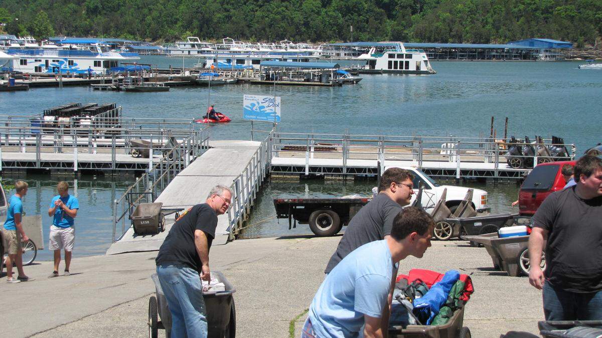 Dan Garry, center, of Shelby Township, Micihgan, was one of more than a dozen people who rented a houseboat at Lake Cumberland State Dock Memorial Day weekend to hold a bachelor party for his son, David, who is getting married next weekend. Here, they load supplies into carts to take to the boat on 5/24/2013. Bill Estep photo