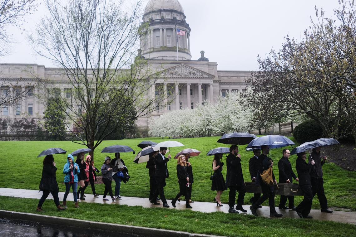 Under a steady morning rain, EKU students and alumni carry an empty casket symbolizing the recently cut EKU theater department during a procession to "A Funeral for Higher Education at the Capitol in Frankfort, Ky. on Monday, April 23, 2018.