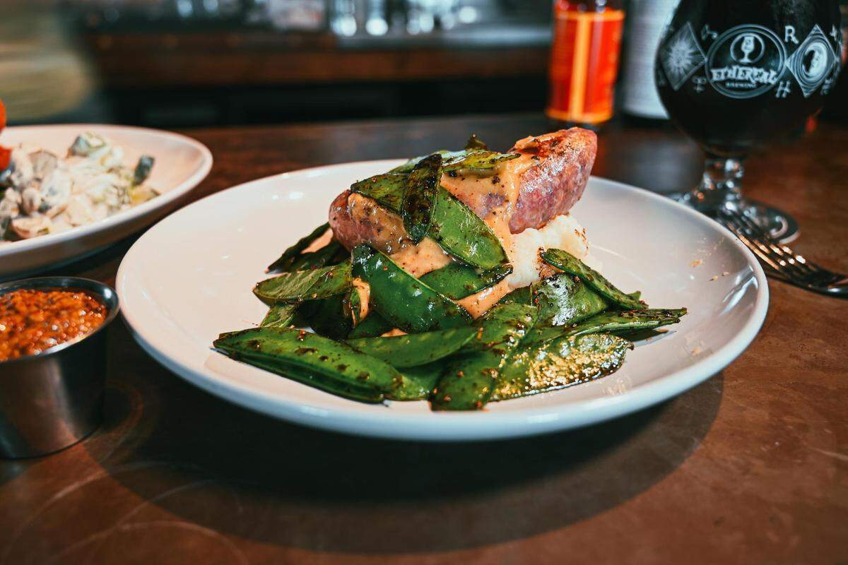Bratwurst & Mash featuring house ground and cased Sunwatch Homestead pork bratwurst, whipped potato, au jus gravy and snow peas at Salt & Vinegar.