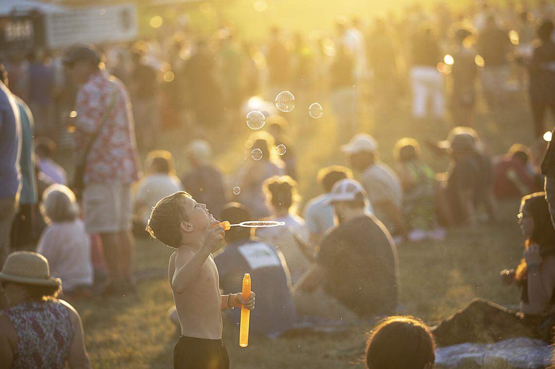 Cyrus Tipton, 7, of Danville, blows bubbles before the start of Old Crow Medicine Show at the Railbird Festival at Keeneland in Lexington, Ky., Saturday, Aug. 10, 2019.