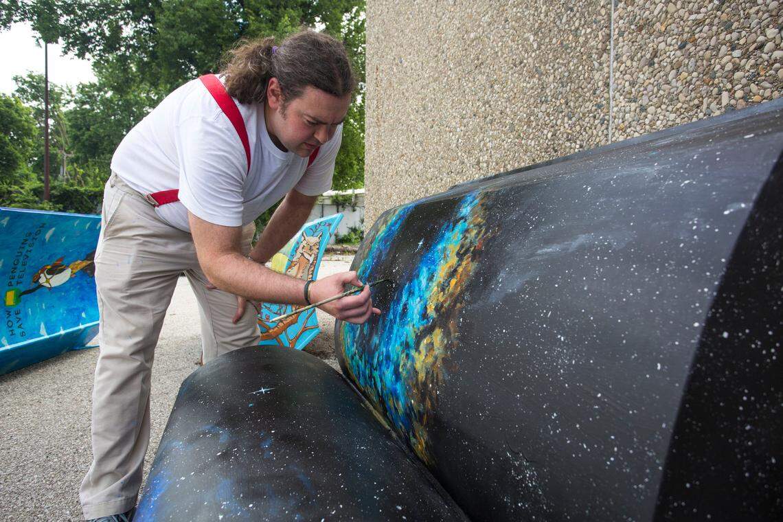 Stevie Moore touches up his bench for the an art installation of book shaped benches being unveiled on Tuesday. Moore's bench is based on the book "The Man Who Fell to Earth" by Walter Tevis. "I'm a big sci-fi fanatic," Moore said as his reason for choosing the design.