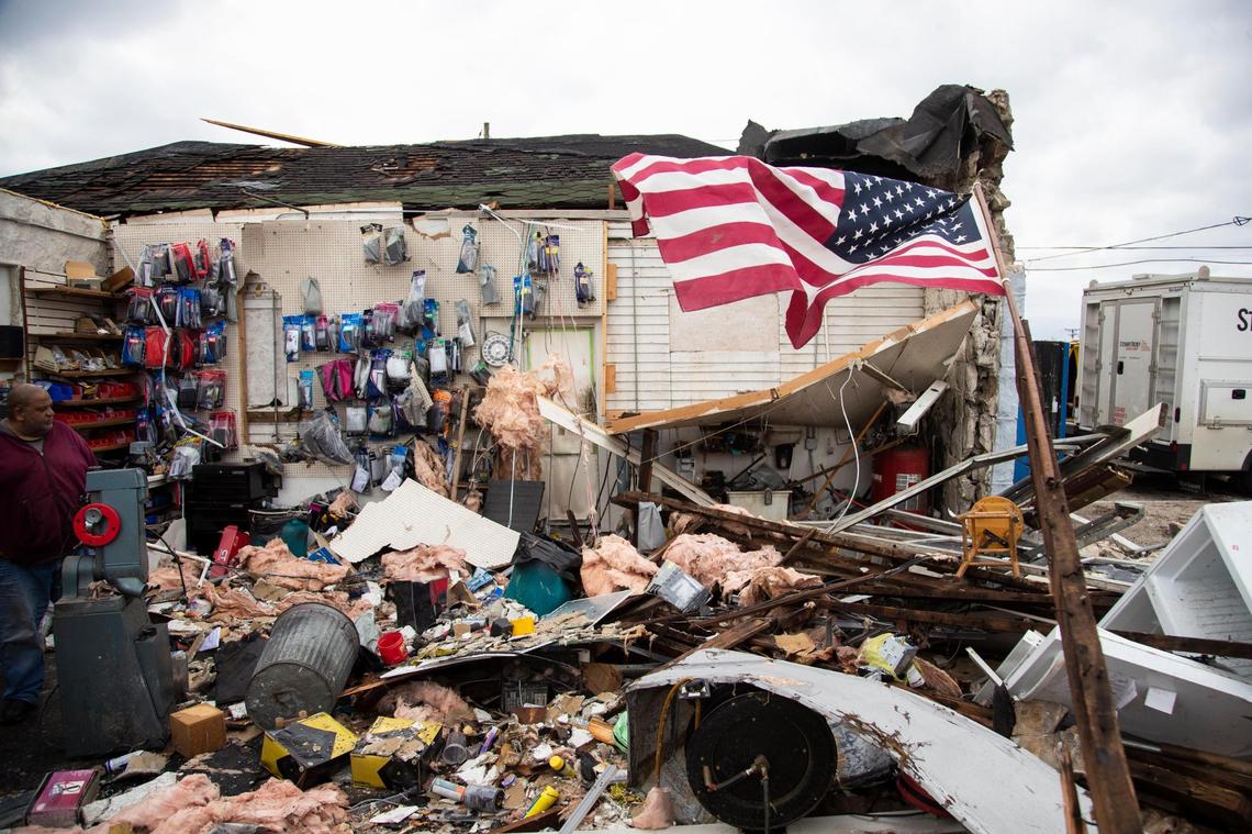 An American flag flies in the rubble of Total Image Audio Inc. on the 31W By-Pass road after a tornado came through the area in Bowling Green, Ky., Saturday, December 11, 2021.