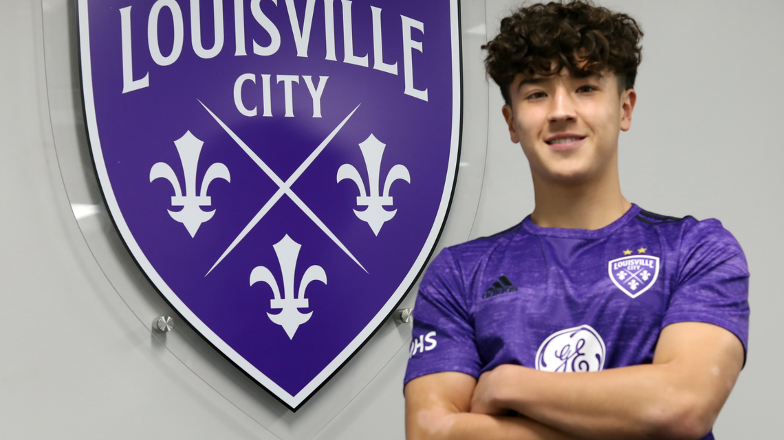 Owen Damm poses in front of the Louisville City FC logo. Damm, a graduate of Woodford County High School, is the latest signing by Louisville City FC from the team’s youth academy.