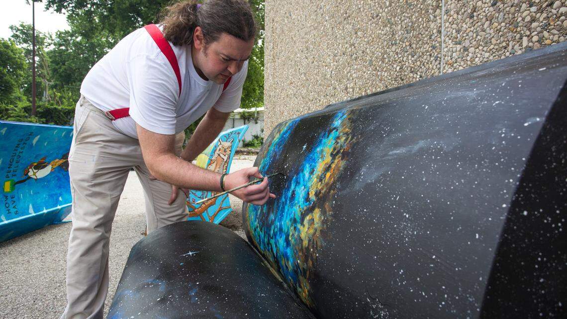 Stevie Moore touches up his bench for the an art installation of book shaped benches being unveiled this summer. The Lexington council is considering whether it should have a dedicated funding source for larger public art projects such as the bench project. More than 250 cities across the country have a dedicated funding source for public art.