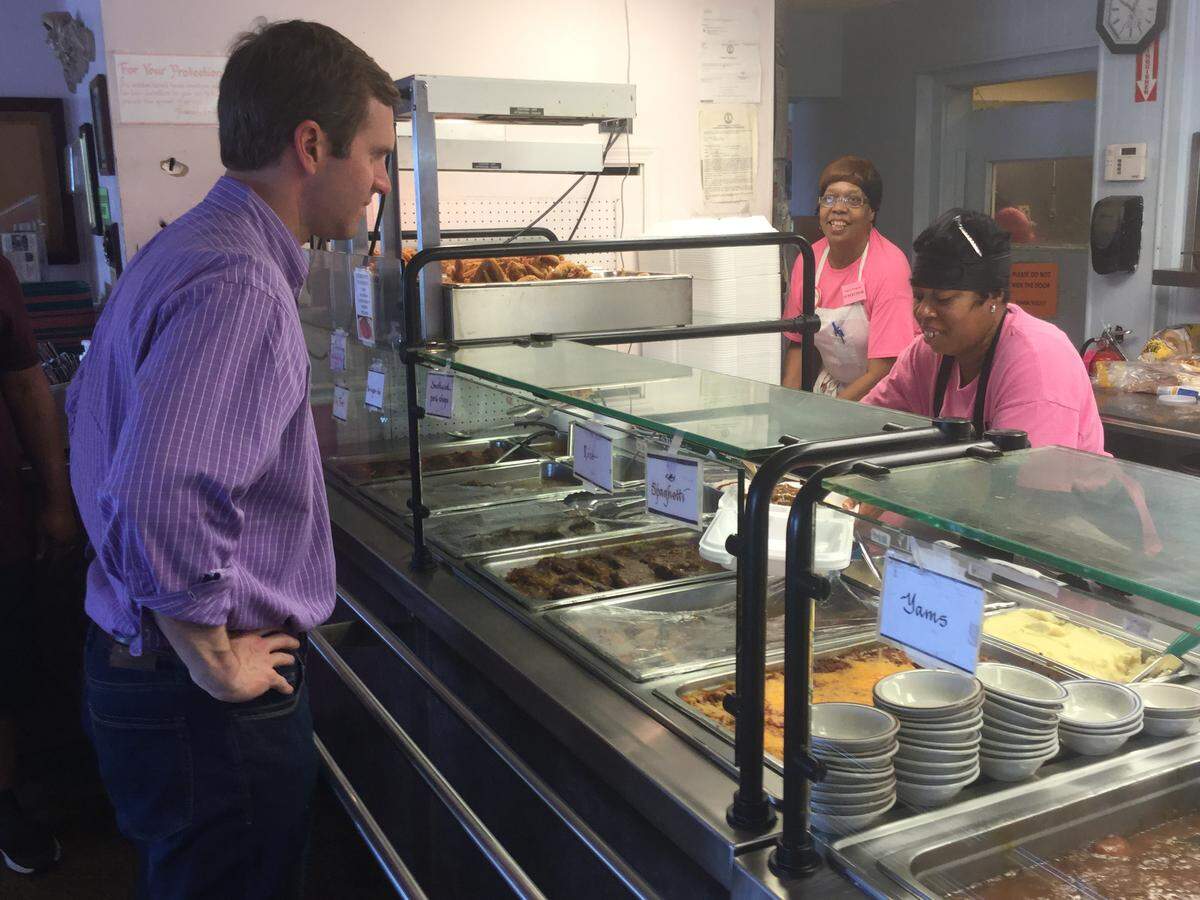 Democratic gubernatorial candidate Andy Beshear grabs a hearty lunch of pork chop, mac and cheese and collard greens from Rochella Arnold at Franco’s Restaurant in Louisville Saturday, May 18, 2019, during a break from the campaign trail.