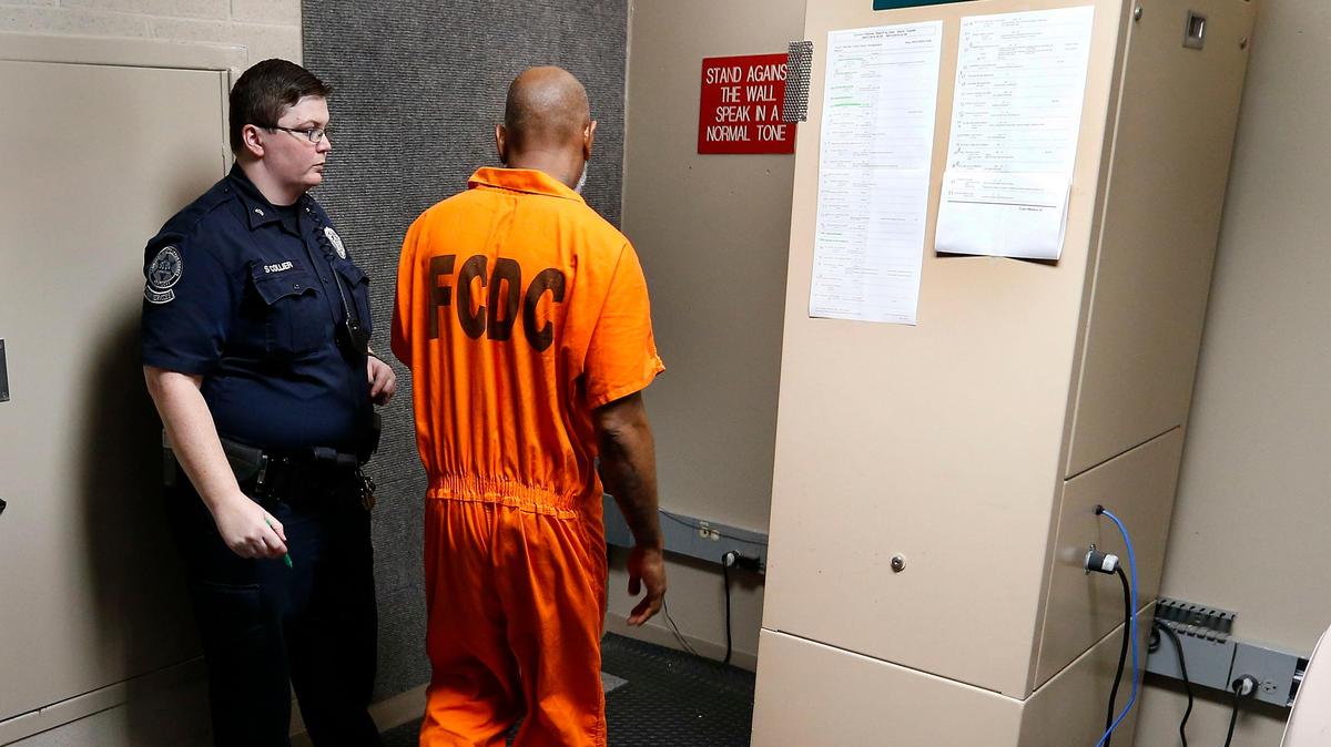 Cpl. Sam Collier led an inmate to the camera and monitor for a district court video arraignment in the Fayette County Detention Center 600 Old Frankfort Pike. The inmates entered a small room where they stood against a carpeted wall and communicated with the judge via video connection.