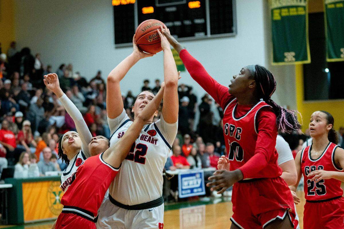 Sacred Heart’s Angelina Pelayo (22) grabs a rebound against George Rogers Clark’s Khania Jones (10) and Jailenn Green (4) during their game on Feb. 9 at Atherton High School.