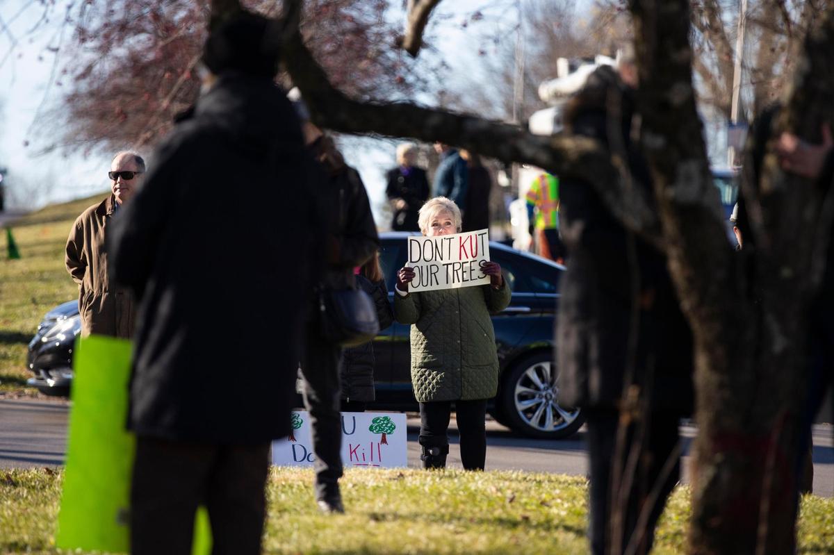 A protester stood in front of trees targeted for removal by KU before police told the demonstrators to move Monday.