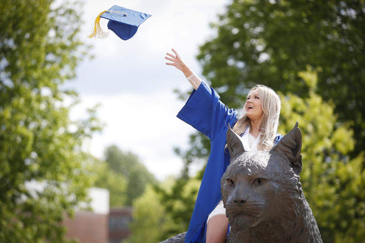 Morgan Moses, of Williamsburg, throws her mortarboard while sitting on Bowman, the wildcat sculpture, as her mother takes pictures at the University of Kentucky Thursday, May 7, 2020. UK has postponed Spring commencement do to the coronavirus pandemic, “It’s bittersweet because I have worked so hard, but I know UK’s gonna find a really proper way to celebrate all of our accomplishments,” she said.