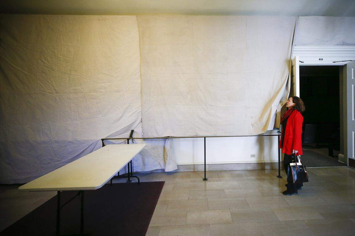 Marcy Deaton, of Lexington, an attorney in the Office of Legal Counsel at the University of Kentucky, pulled back a curtain to view a controversial mural Wednesday at Kentucky’s Memorial Hall. The mural was covered on Tuesday following demands from student groups.