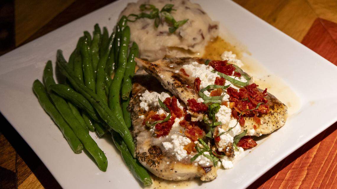 Chicken Henry ($18.99) at Ford’s Garage, photographed Tuesday, Nov. 4, 2025, in Lexington, Ky., is marinated chicken breast, topped with Chardonnay lemon butter sauce, goat cheese, basil and sun-dried tomatoes. It comes with a choice of two sides (green beans and mashed potatoes, shown here).