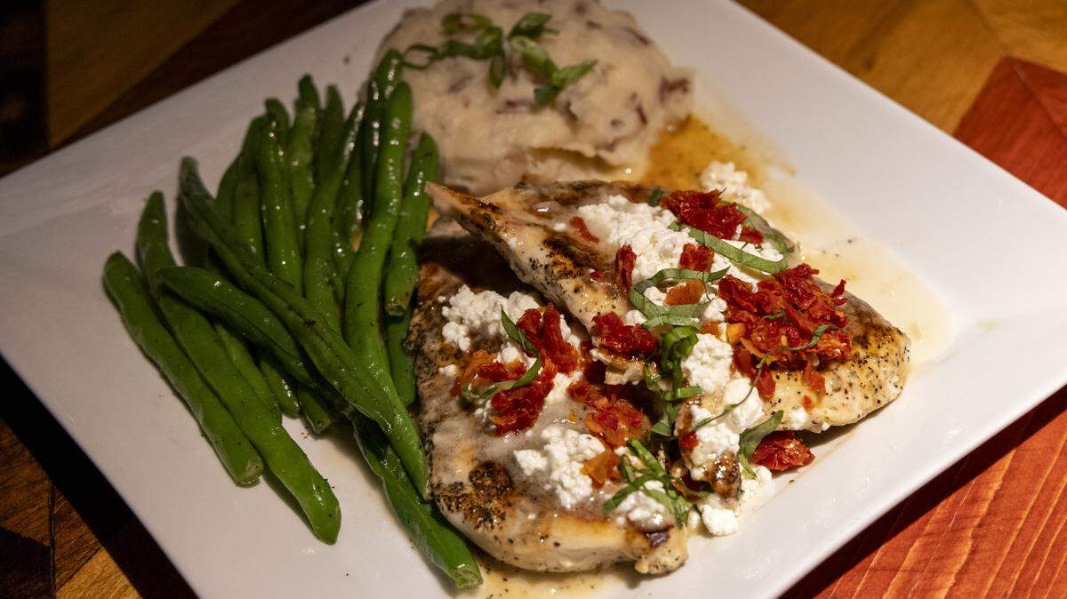 Chicken Henry ($18.99) at Ford’s Garage, photographed Tuesday, Nov. 4, 2025, in Lexington, Ky., is marinated chicken breast, topped with Chardonnay lemon butter sauce, goat cheese, basil and sun-dried tomatoes. It comes with a choice of two sides (green beans and mashed potatoes, shown here).