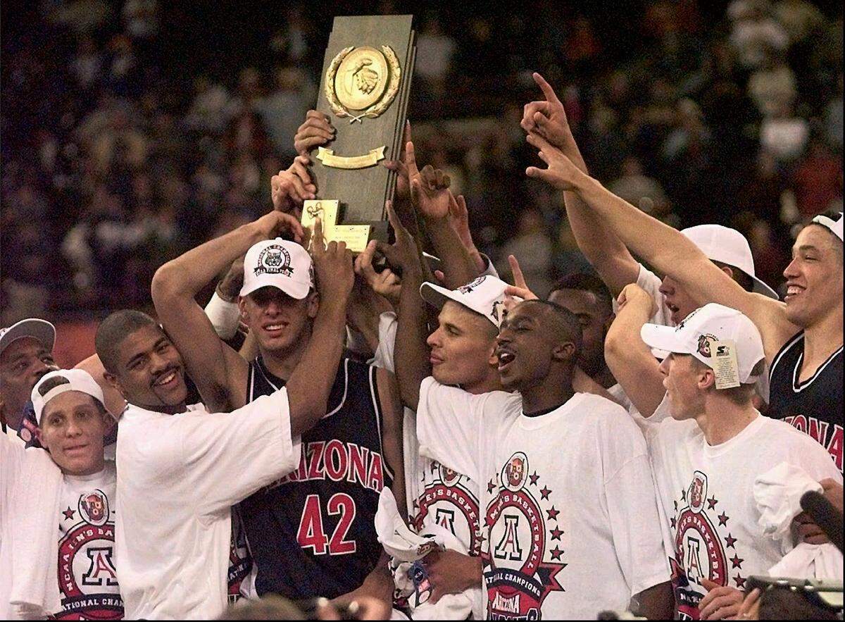 Arizona teammates celebrate with the NCAA Division I Trophy Monday after they defeated Kentucky 84-79 in overtime at the NCAA National Championship game at the RCA Dome in Indianapolis, Indiana on March 31, 1997.. (Charles Bertram - Lexington Herald-Leader)