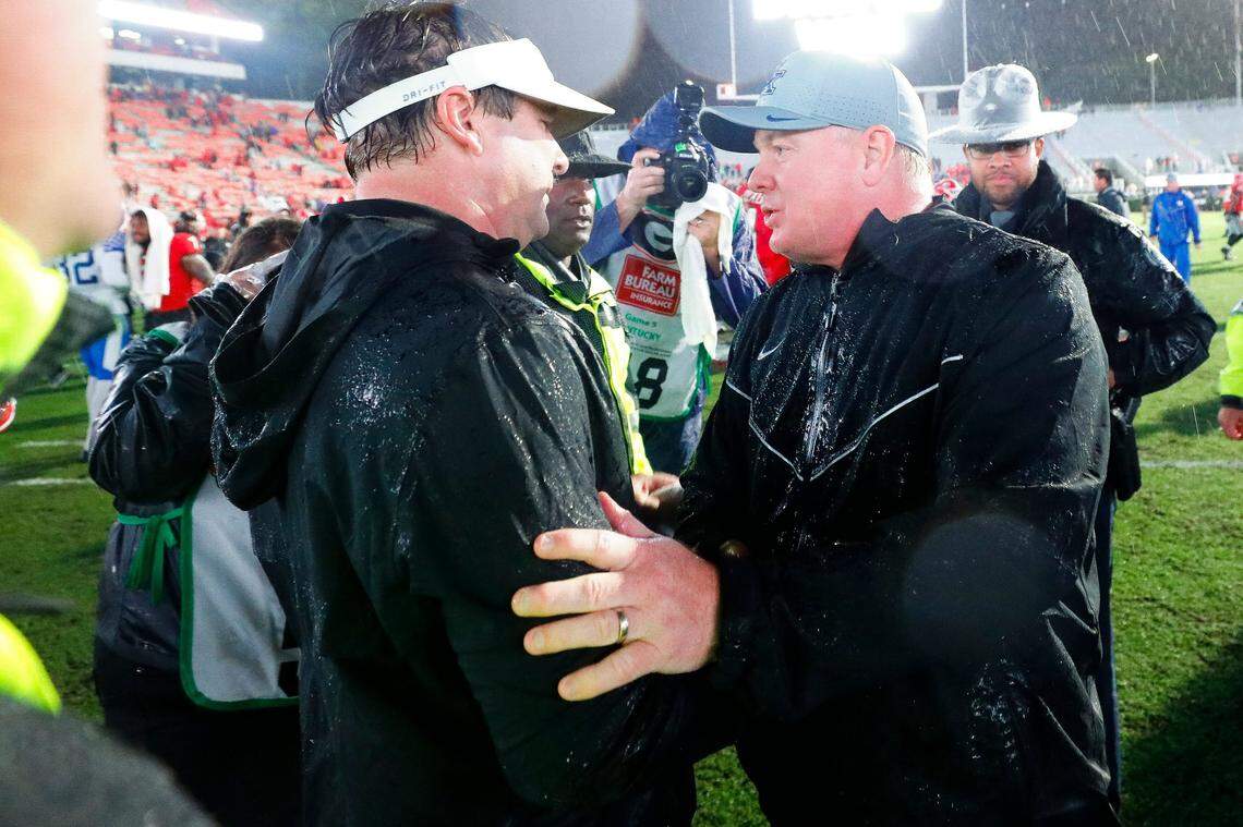A pair of drenched coaches, Kentucky’s Mark Stoops, right, and Georgia’s Kirby Smart met after the Bulldogs shut out the Wildcats 21-0 in a driving rain storm in 2019 at Sanford Stadium.