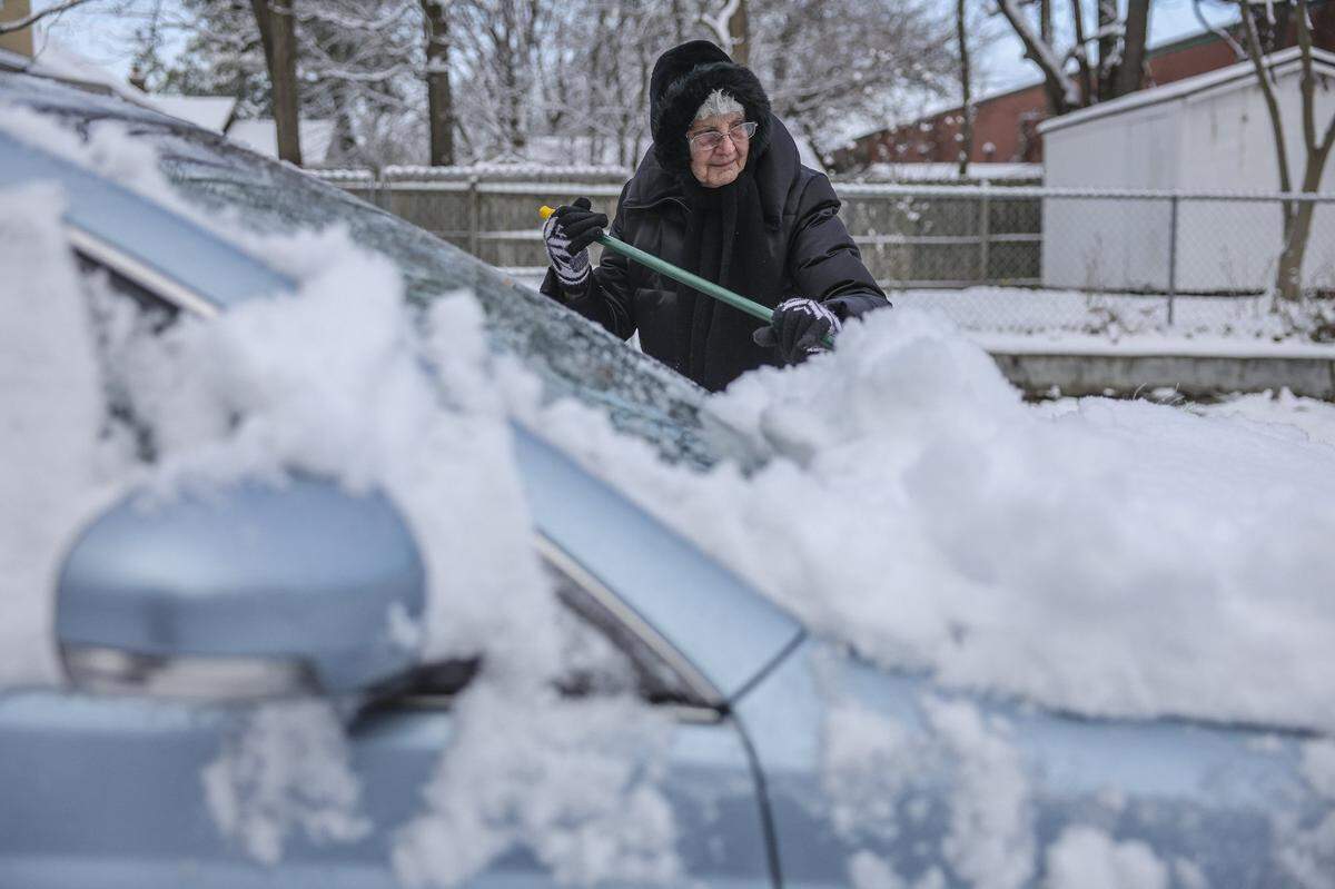 Dora Hisel clears snow from her car in Lexington, Ky., Friday, Dec. 12, 2025.