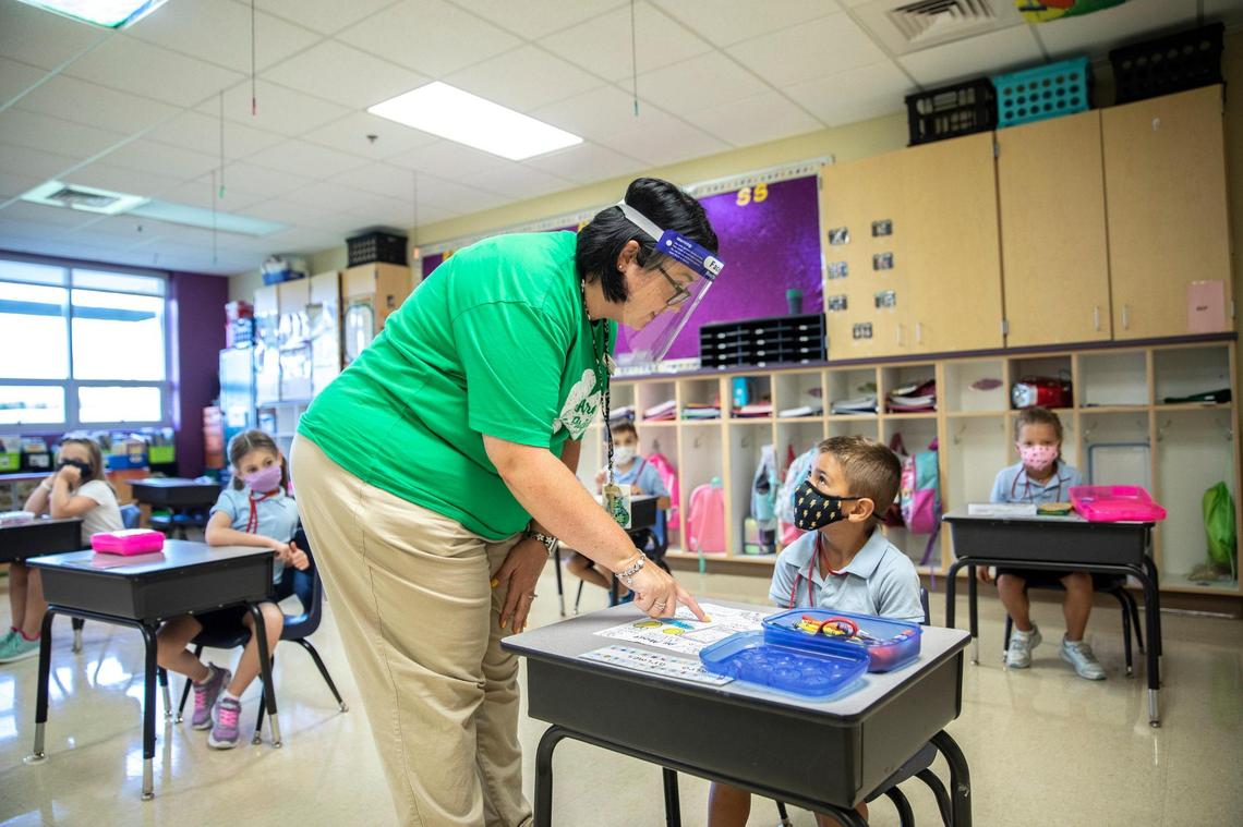 First grade teacher Kelli Coleman helps Ramiro Grimes complete an “all about me” assignment at Good Shepherd Catholic School in Frankfort, Ky., on the first day of school, Monday, Aug. 17, 2020.