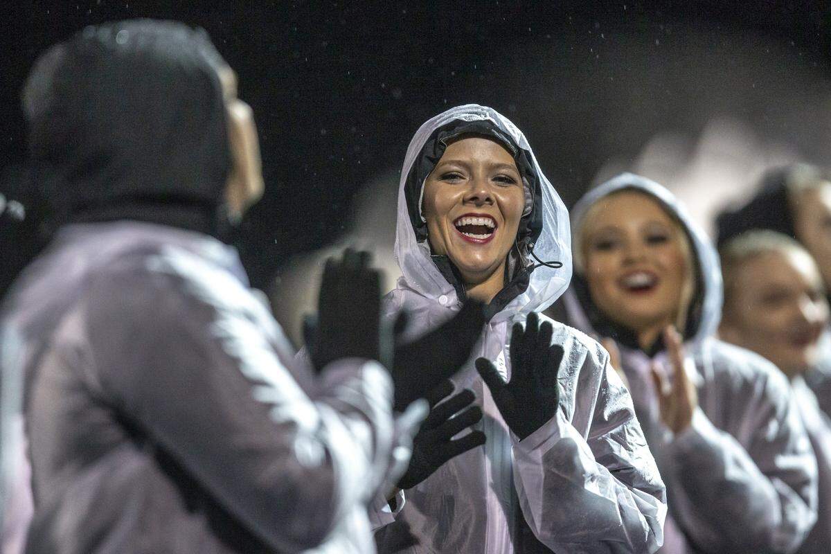 Harlan County cheerleader Baili Boggs, second from left, cheers in the rain.