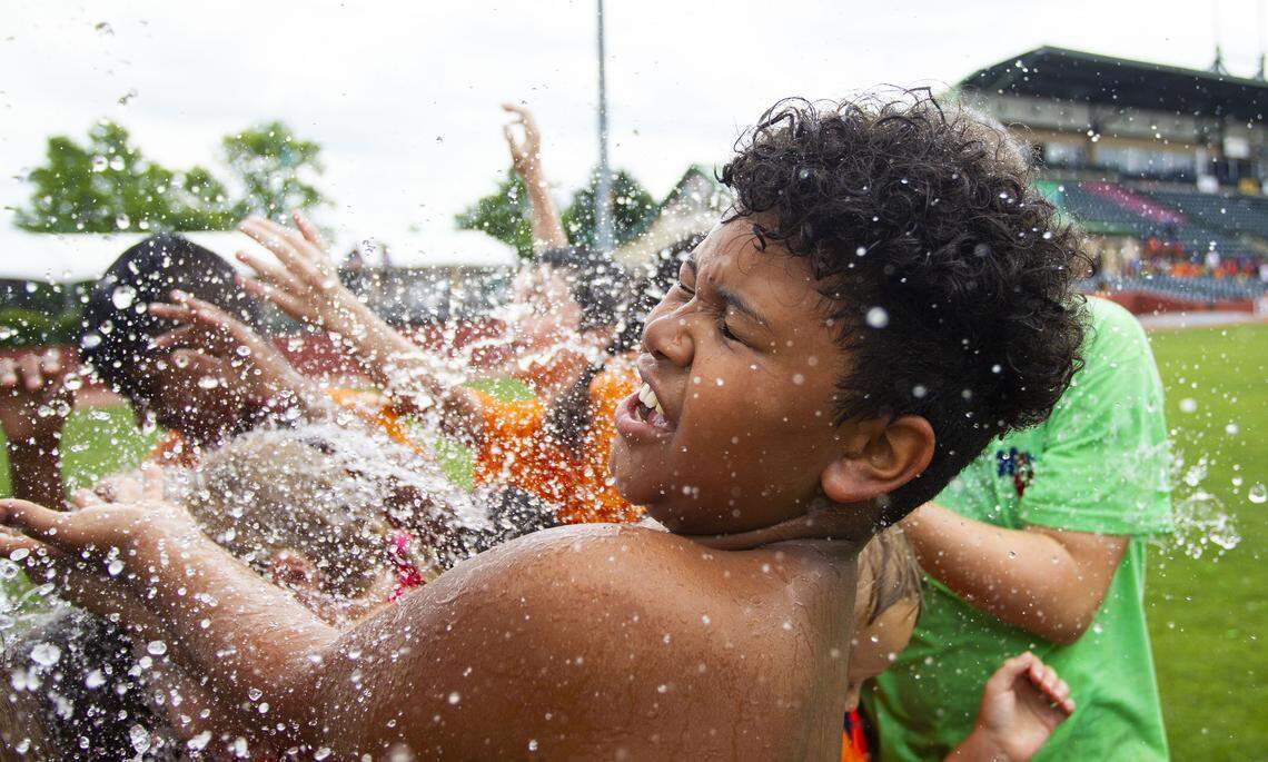 Brandon Marcus, 10, reeled as he is hit with water thrown from a bucket by Lexington Legends players as part of their Splash Day that took place after their game on Wednesday at Whitaker Bank Ballpark.