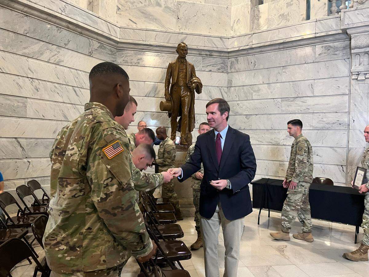 Beshear hands out Team Kentucky branded coins to National Guard members at an event honoring those deployed to the U.S.-Mexico border.