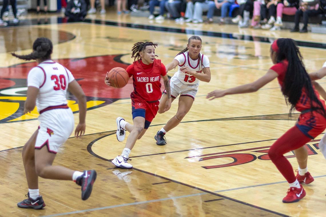 Sacred Heart’s Amirah “Tootie” Jordan (0) drives past George Rogers Clark’s Jaylynn Goodwin (13) during their game in Winchester on Wednesday.