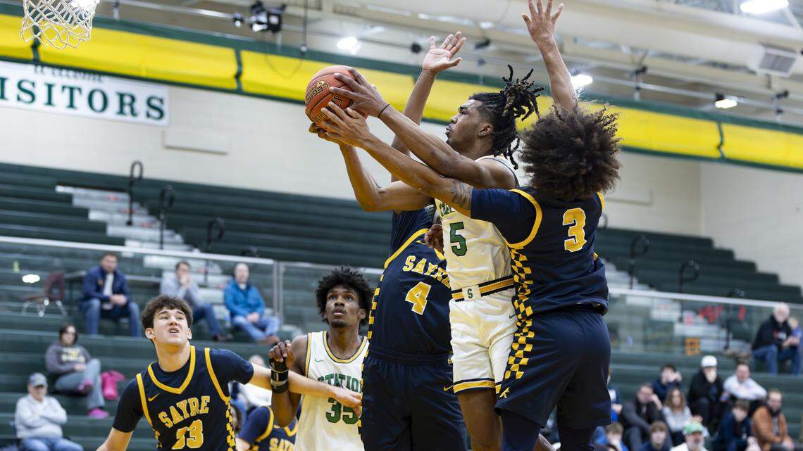 Bryan Station’s Amari Owens (5) split Sayre’s Sayvion Staley (4) and Caden Jones (3) as Beau Perry (23) tried to box out Taeshawn Adams during the Defenders’ 65-42 win at Bryan Station High School on Sunday.