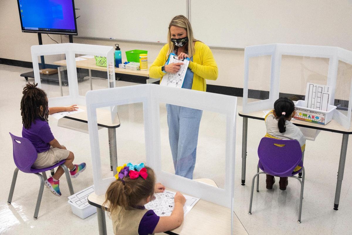 Miss Jennifer Lopez gives instruction to students at their desks working on an exercises behind plastic desk shields in the kindergarten classroom at the Rise Stem Academy for Girls in Lexington, Ky., Monday, October 19, 2020. Students have returned to classes at the academy with a maximum of 7 students in the classroom with masks on and plastic dividers at their desks.